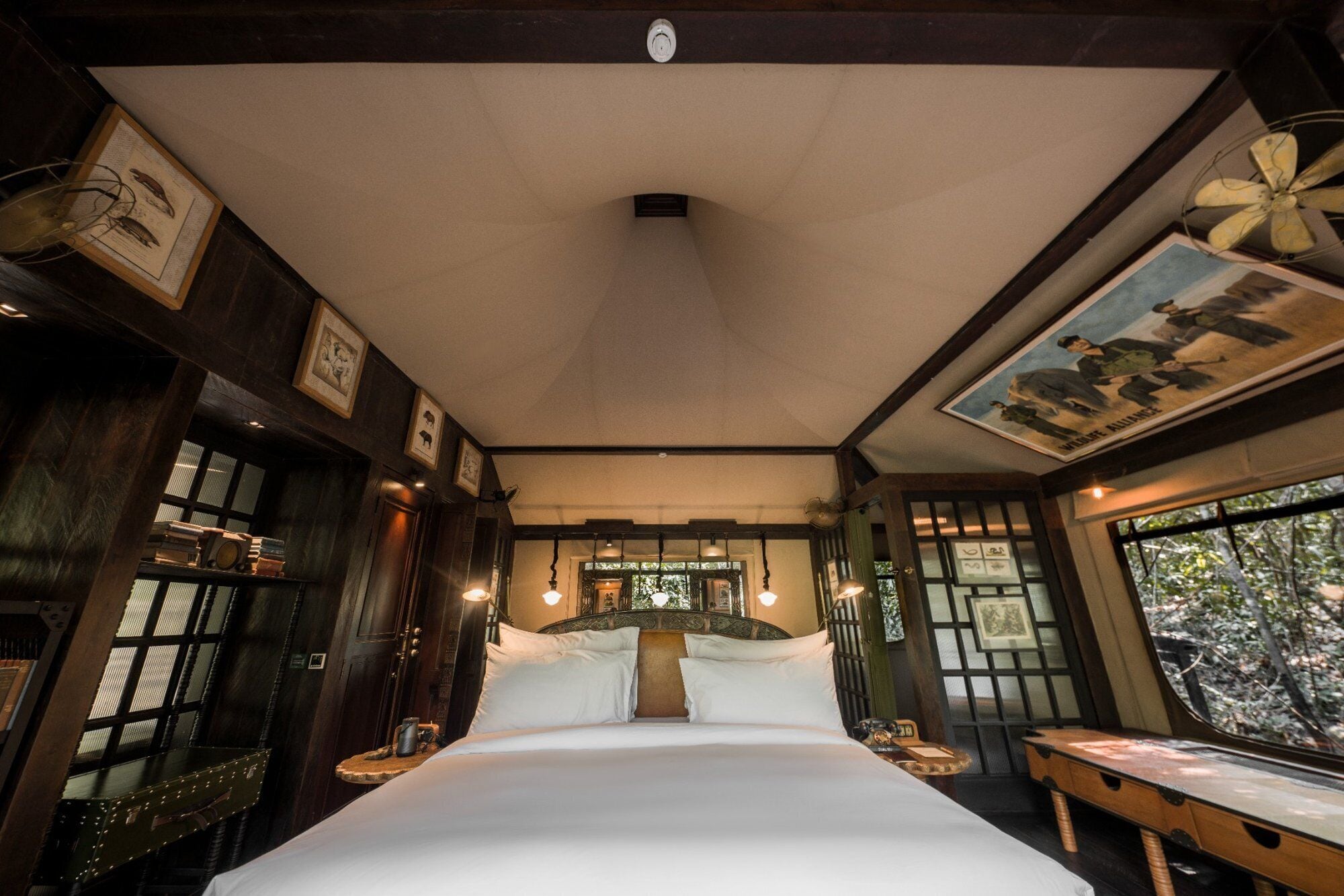 A bedroom with a large bed, wooden walls, and a ceiling fan.