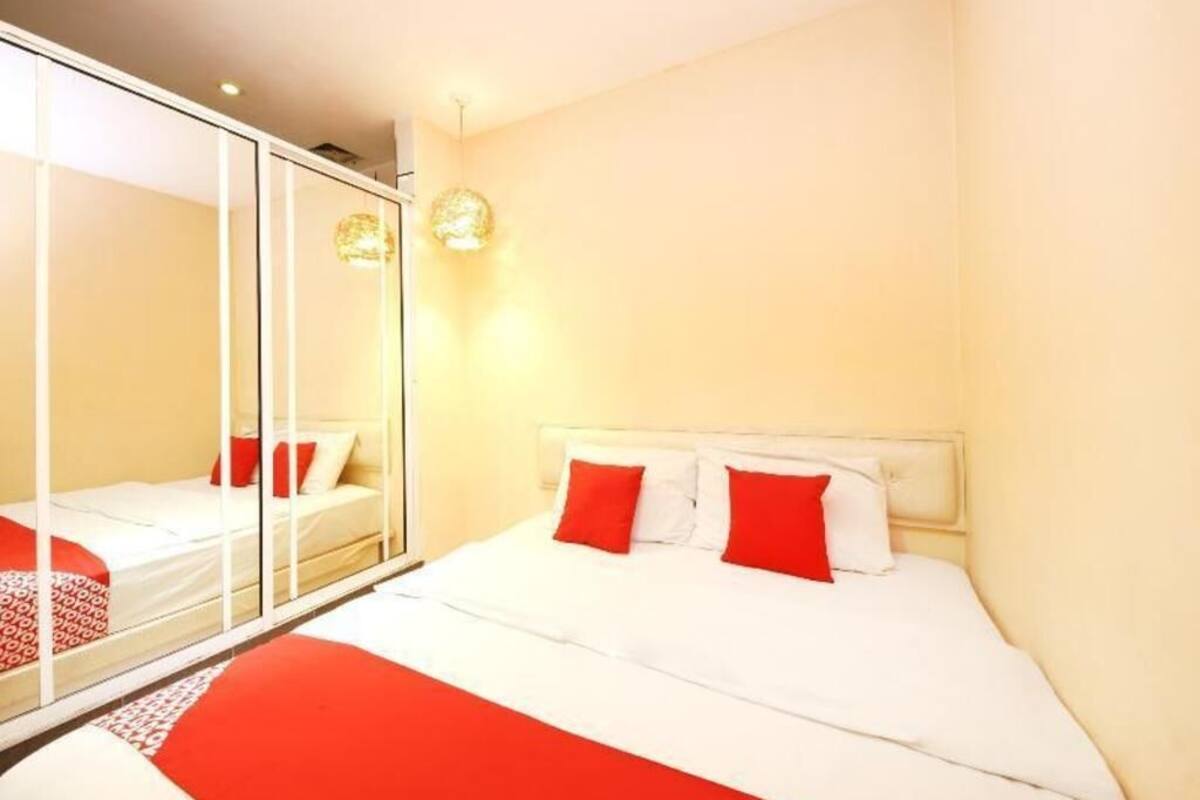 A bedroom with a bed, a mirror, and two wall-mounted lights.