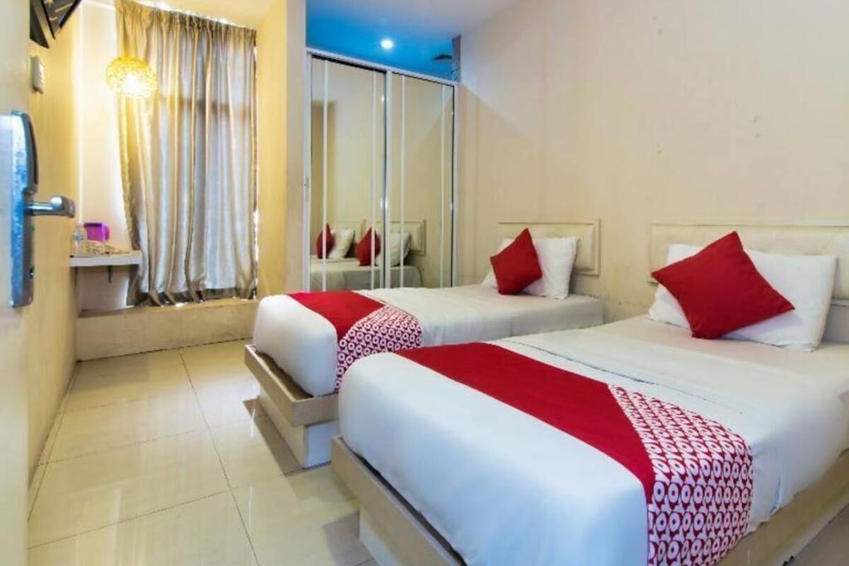 A hotel room with two beds, a mirror, a wardrobe, and a bathroom.