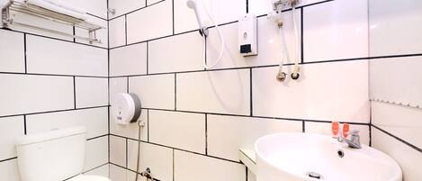 A bathroom with white tiles, a toilet, a sink, and a shower with a handheld showerhead.