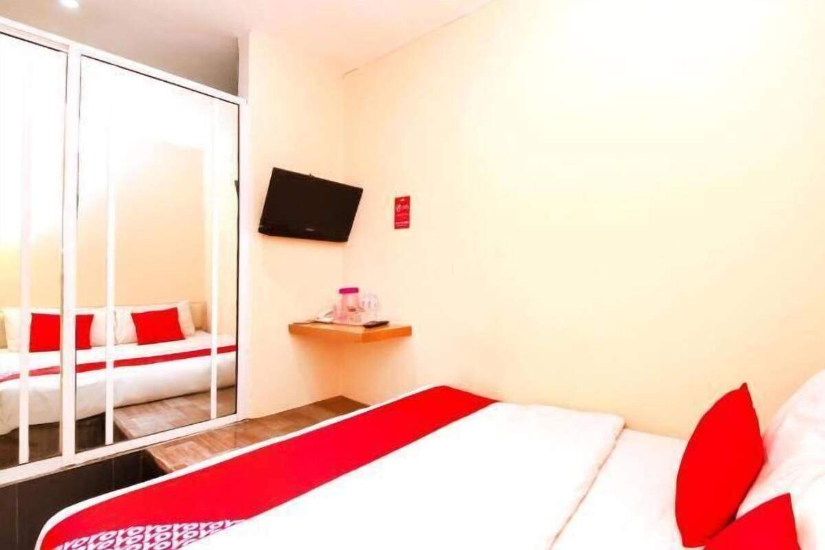 A hotel room with a bed, a TV, a small table, and a mirror.