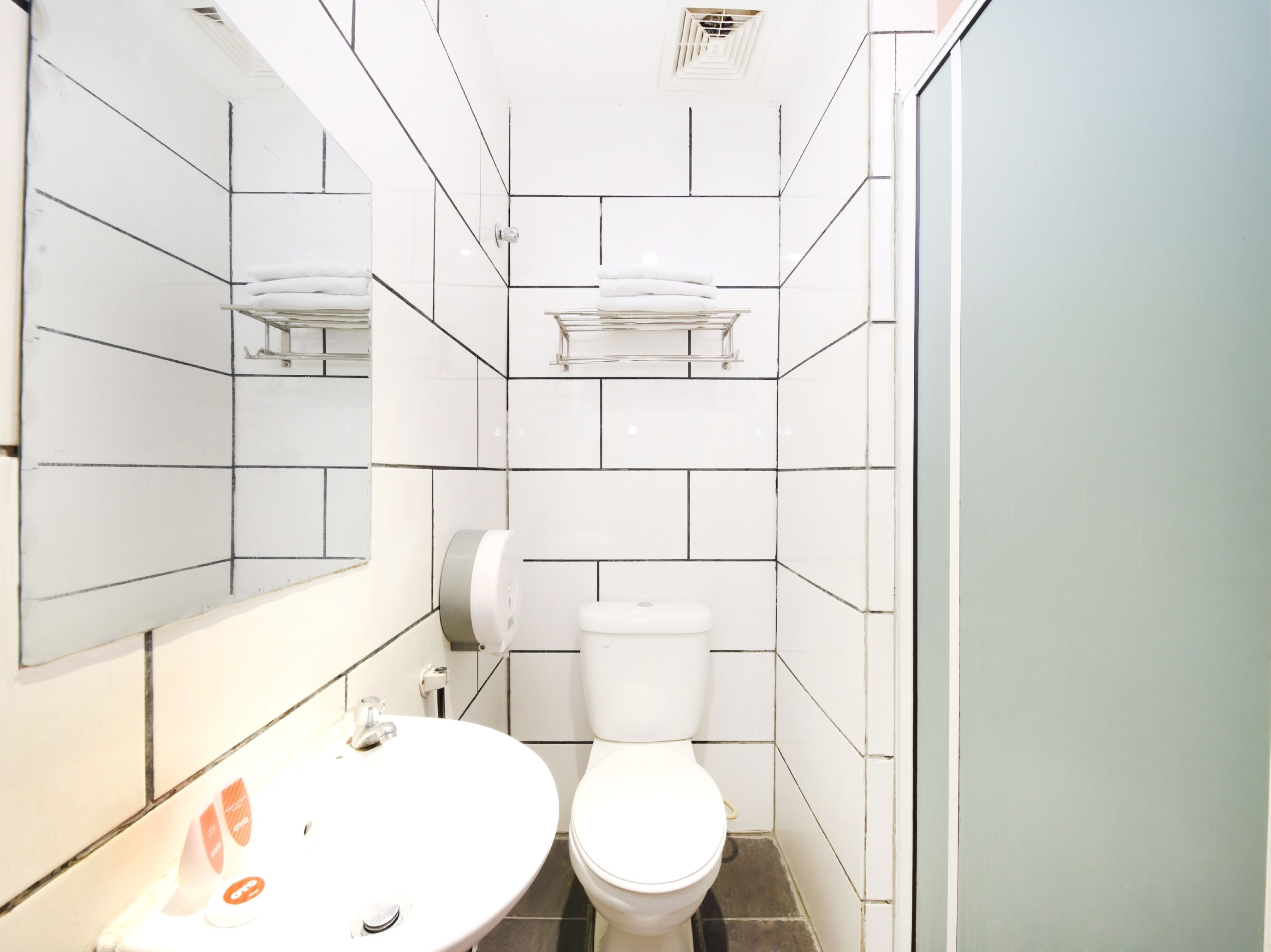 Un baño pequeño con un lavamanos, inodoro y espejo blancos.