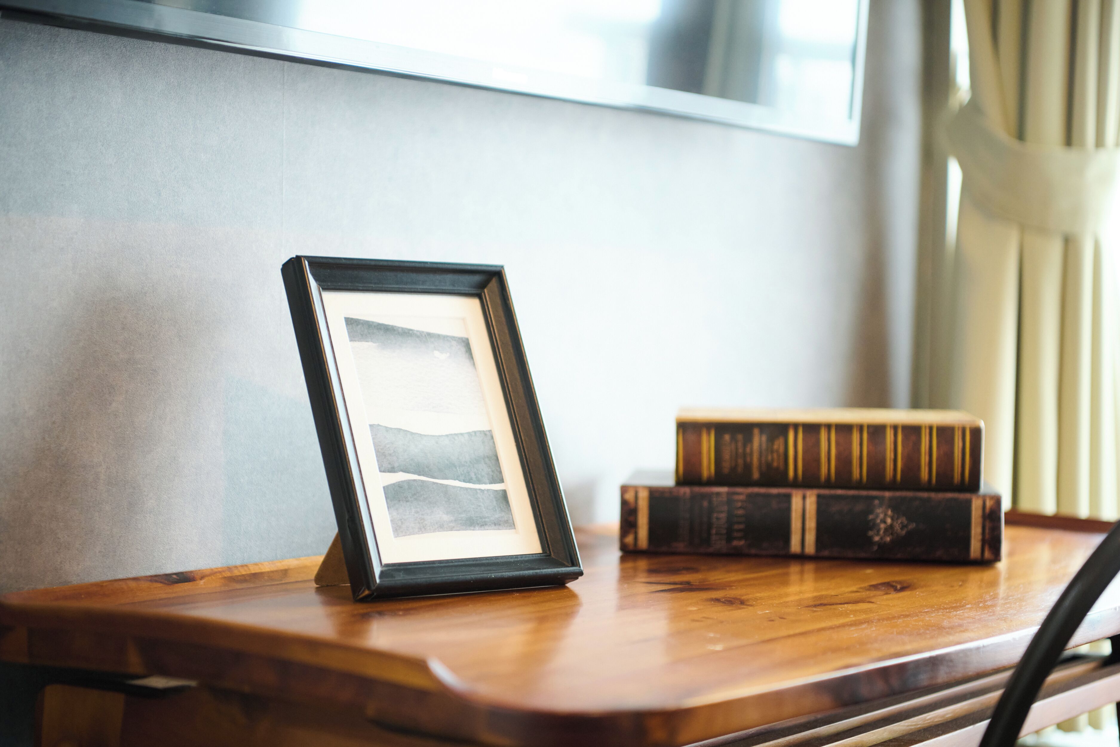 Un cuadro en marco sobre una mesa de madera, con libros apilados a un lado.