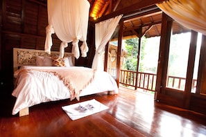 A wooden room with a bed, a balcony, and a view of greenery. - Umah Tis Sebatu (Tegallalang)