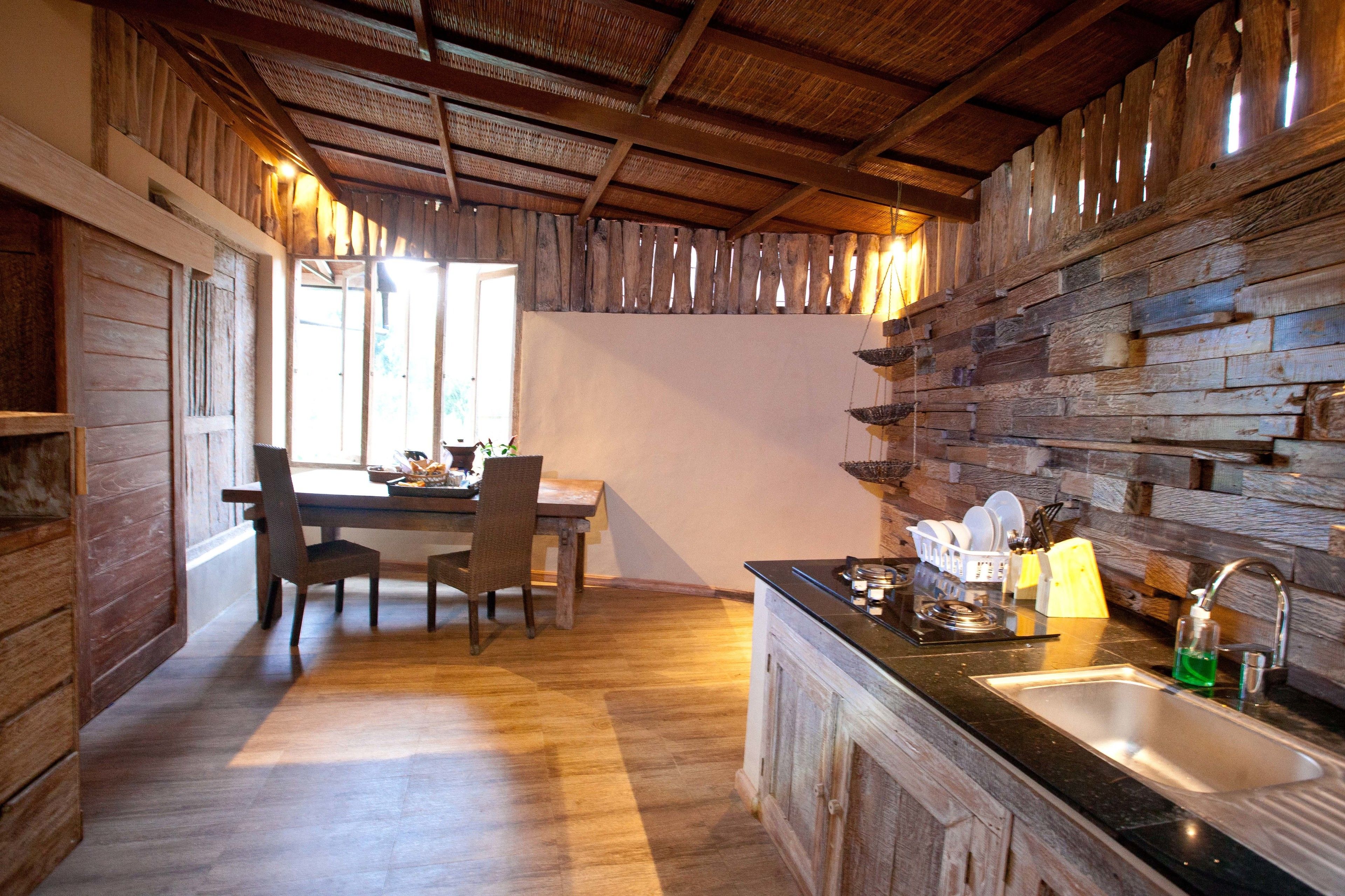 Eine rustikale Küche mit Holzwänden, einem Essbereich mit Stühlen und einem Waschbecken mit modernen Armaturen.
