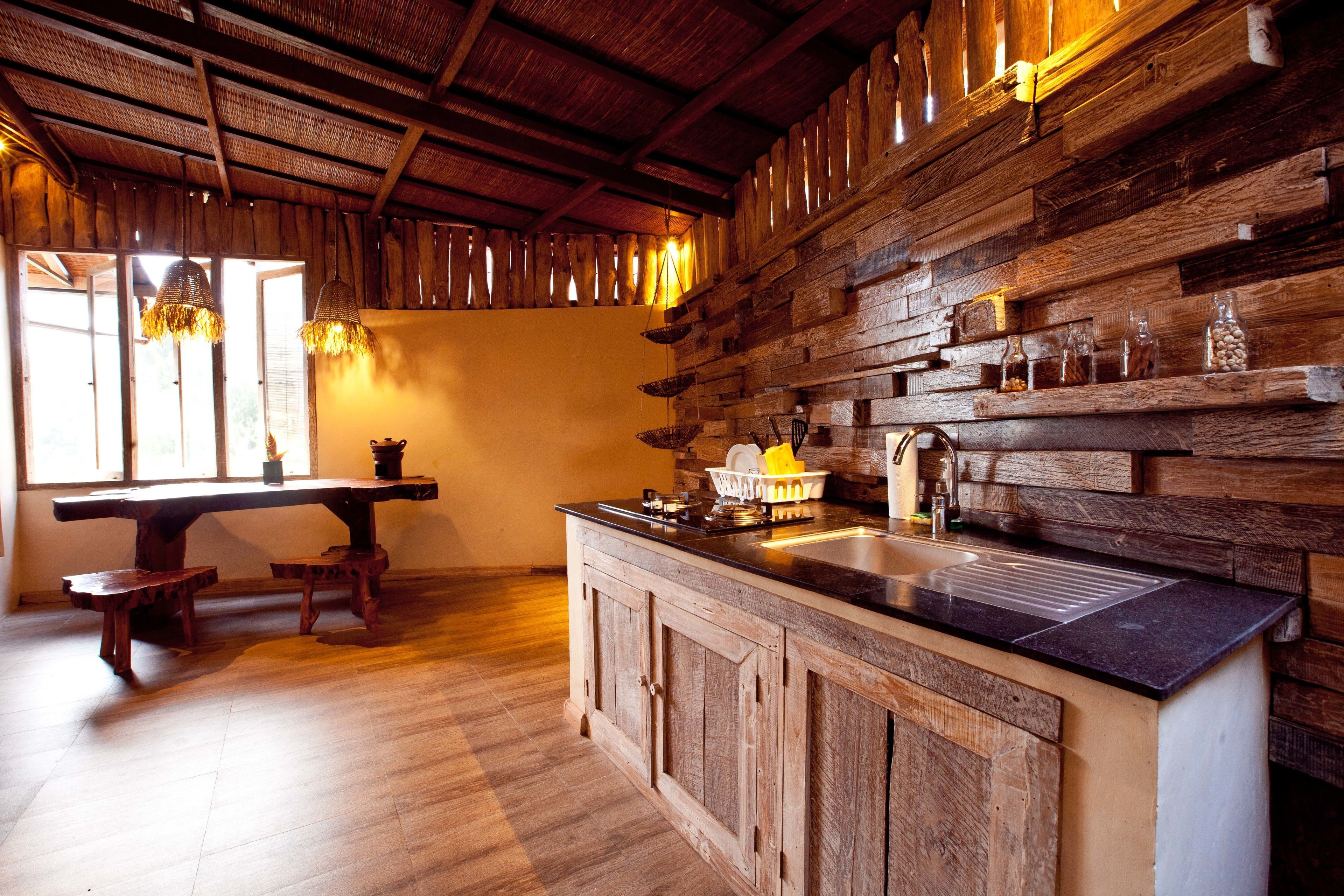 Una cucina rustica con pareti in legno, un'isola centrale con lavello e un'area pranzo con panche.