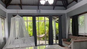 A room with a bed, a sofa, and a large window with curtains. - Siargao Residency (General Luna)