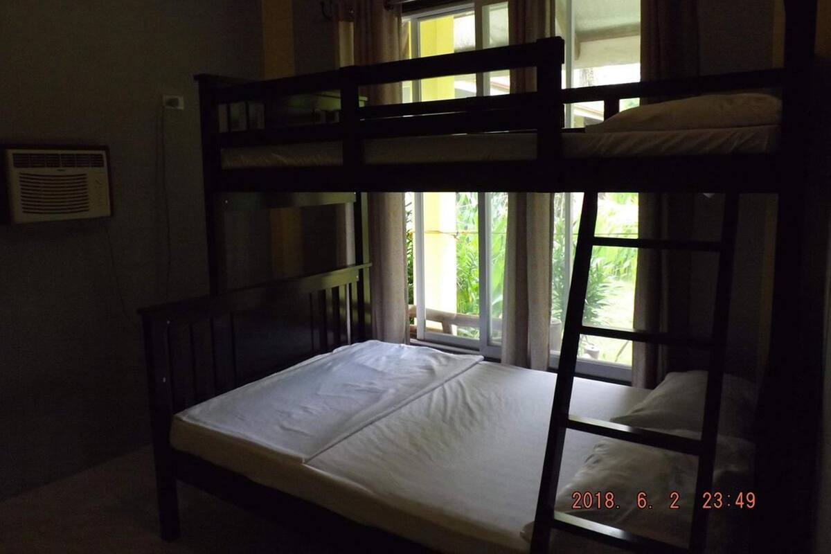 A bunk bed room with a window, a radiator, and a wall-mounted air conditioner.