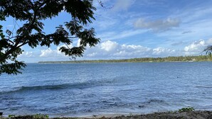 A calm body of water with a distant shoreline, surrounded by trees and clear skies. - Siargao Residency (General Luna)