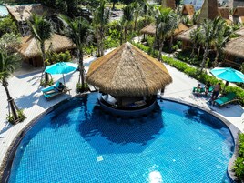 Una piscina con una estructura de techo de paja en el centro, rodeada de sillones de playa y sombrillas.