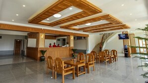 A spacious lobby with a reception desk, wooden ceiling beams, and a staircase leading to upper floors. - Five One Star Hotel (Nyaungshwe)