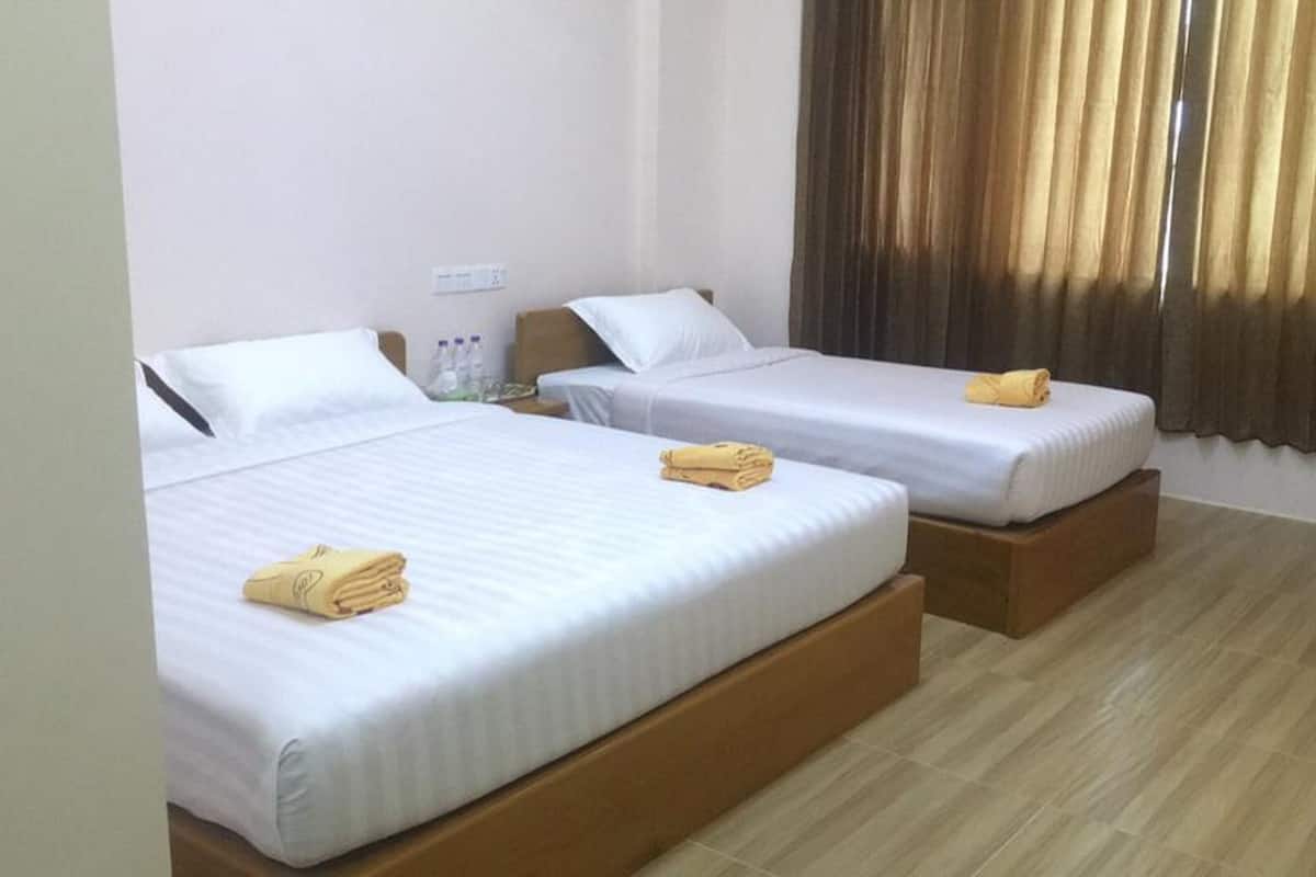 Une chambre d’hôtel avec deux lits, chacun doté d’un sommier en bois, de draps blancs et de serviettes jaunes.