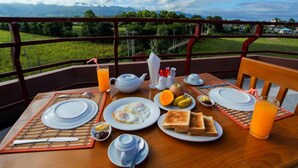 A breakfast table set with plates, toast, eggs, and juice, overlooking a scenic landscape. - Five One Star Hotel (Nyaungshwe)