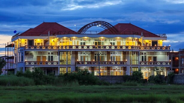 A multi-story hotel with a prominent arched entrance and balconies on each floor. - Five One Star Hotel (Nyaungshwe)