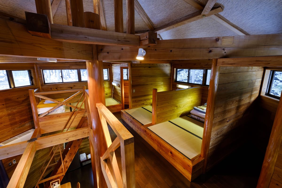 Una cabaña con paredes y suelos de madera, varias ventanas y una escalera.