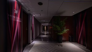 A hallway with a modern design, featuring a potted plant and a digital display indicating room numbers. - HOTEL BAMBOO GARDEN Shin-Yokohama - Adults Only (Yokohama)