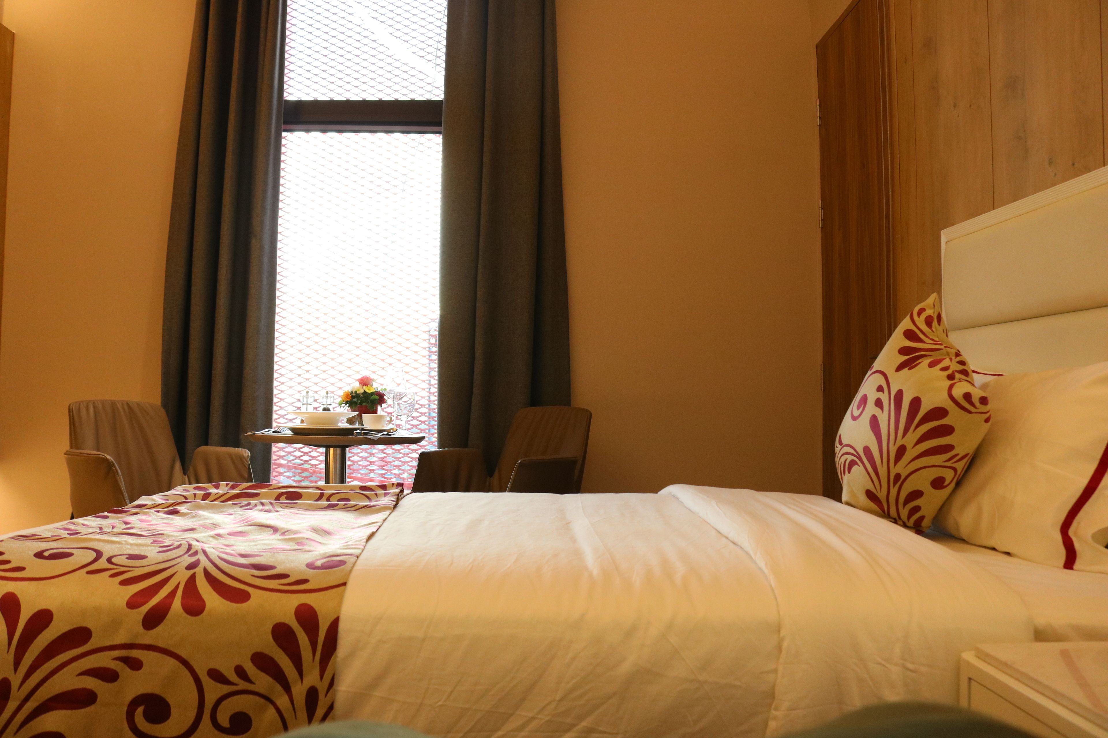 A hotel room with a large bed, a small table with a vase of flowers, and two chairs.