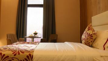 Une chambre d’hôtel avec un grand lit, une petite table ornée d’un vase de fleurs et deux chaises.