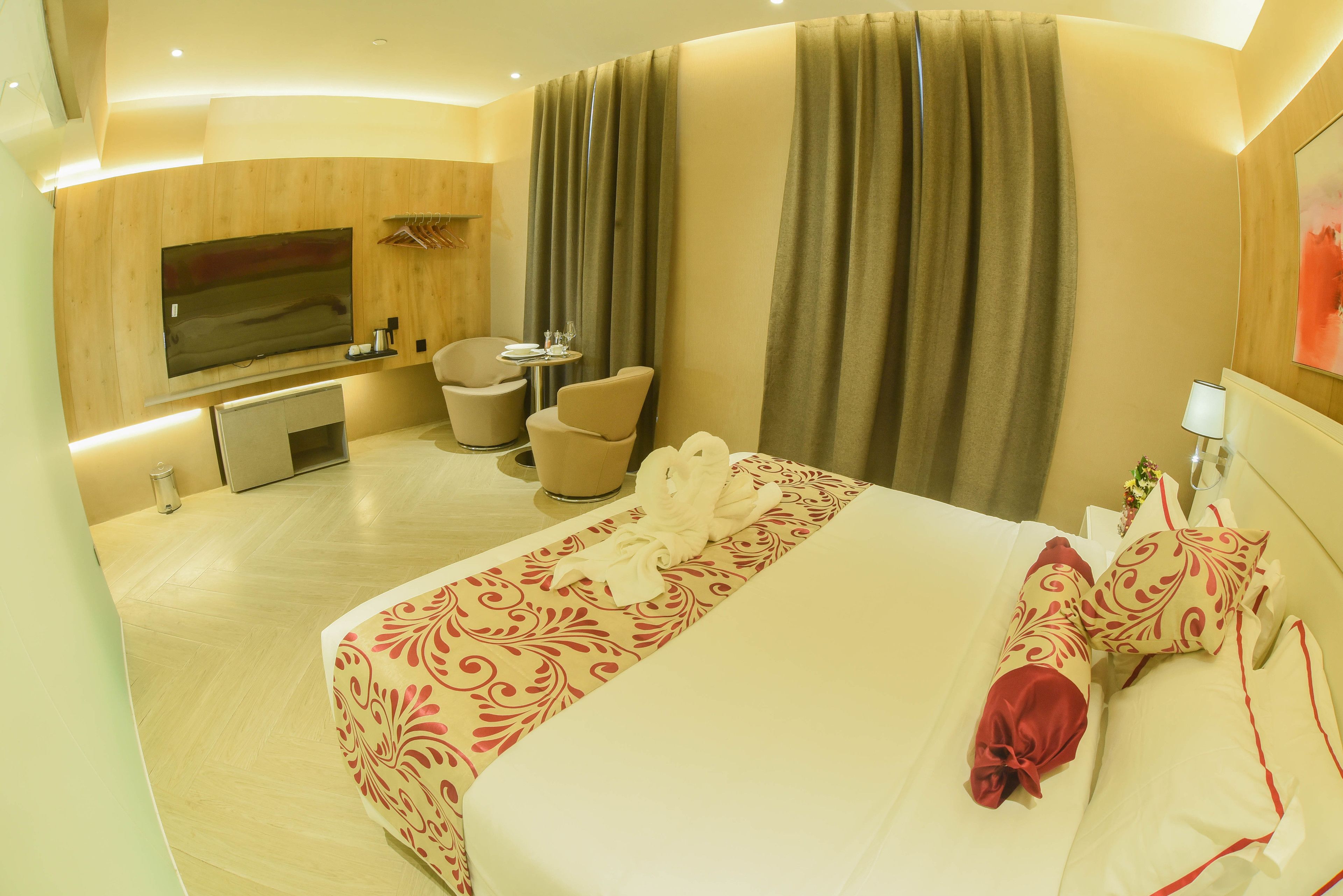 A hotel room with a large bed, a TV, a desk, and a chair.