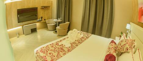 A hotel room with a large bed, a TV, a desk, and a chair.