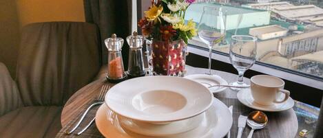 A dining table set with plates, cutlery, and a vase of flowers.