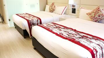 A hotel room with two beds, each with a red and white patterned bedspread, a wooden headboard, and a bedside table with a lamp.