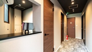 A hotel reception area with a counter, a computer, and a fire extinguisher. - UCHI Asakusabashi (Tokyo)