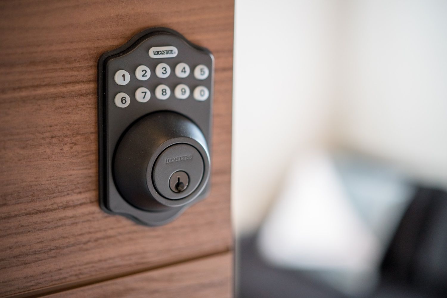A modern electronic keypad lock on a wooden door.