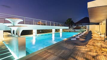 Una piscina al aire libre, sombrillas, sillones reclinables de piscina