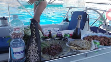 A boat with a table set with snacks, drinks, and a bottle of water.