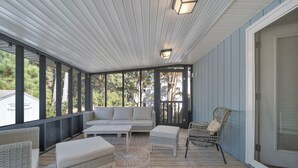 A covered outdoor seating area with a sofa, chairs, and a table. - Beach Pines by Seaside Vacations & Sales (Chincoteague Island)