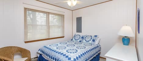 A bedroom with a bed, a chair, a desk, a lamp, and a ceiling fan.