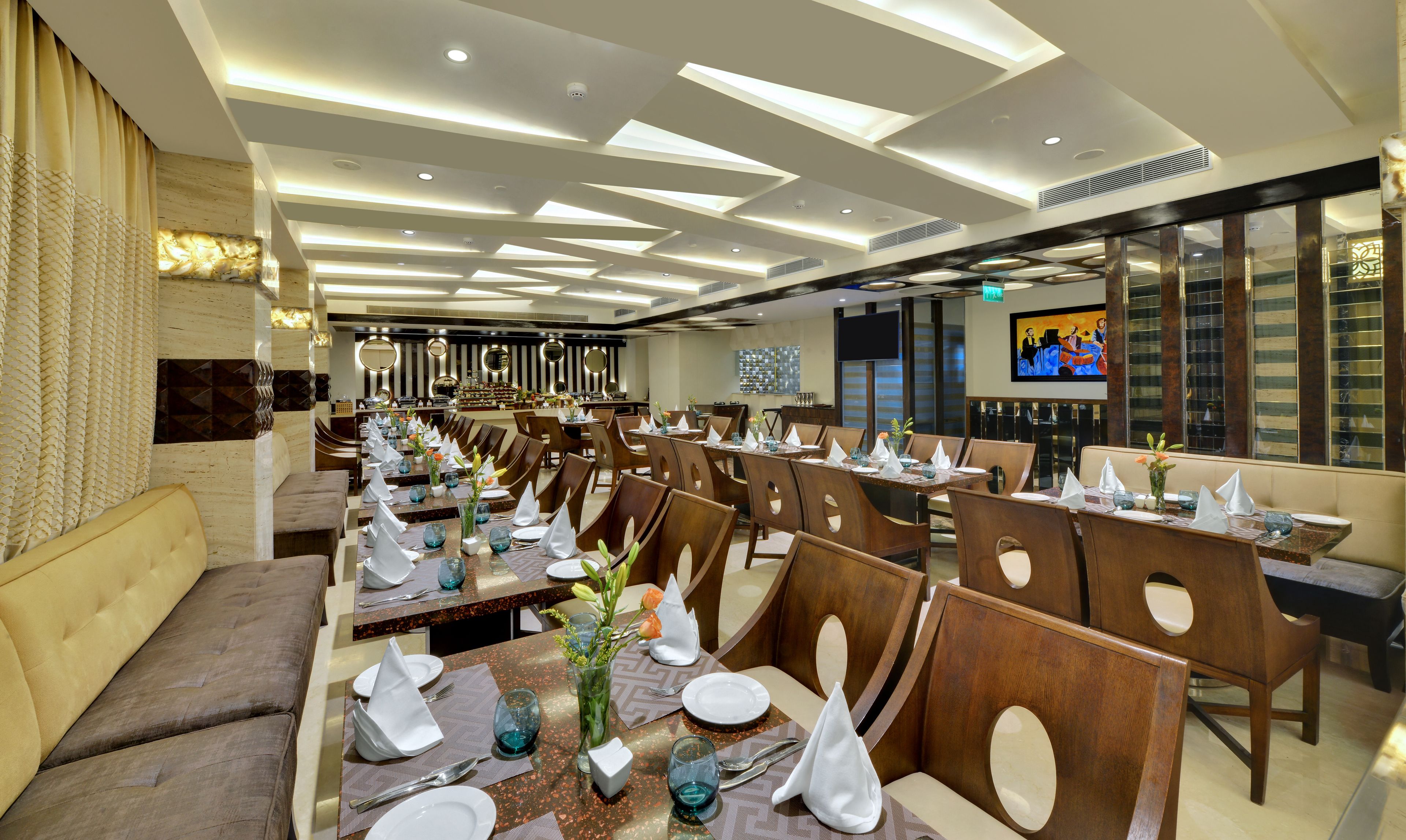 A restaurant with multiple dining tables set with white napkins, plates, and blue glassware.