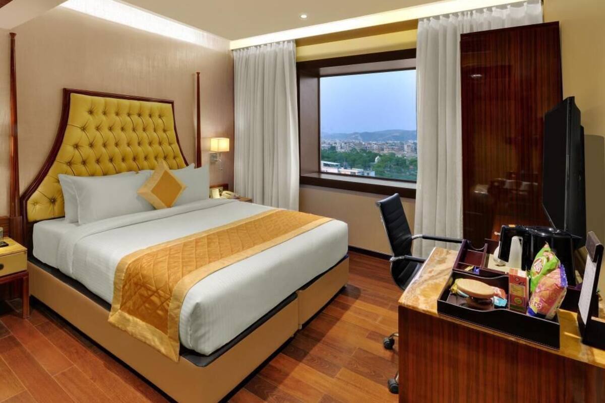 Une chambre d’hôtel avec un grand lit, un bureau équipé d’un ordinateur et une vue sur la ville.