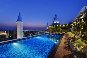 A rooftop pool with a clear view of the city skyline, including two prominent buildings with pointed tops.