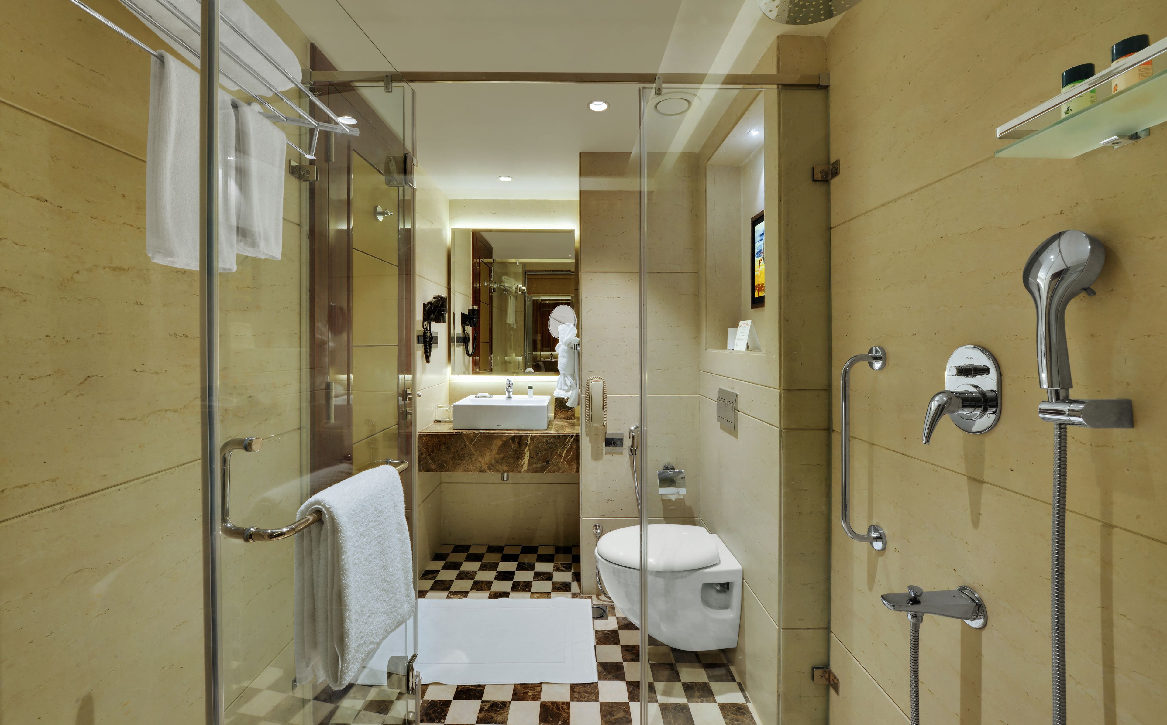 A modern bathroom with a glass-enclosed shower, a white toilet, and a sink with a marble countertop.