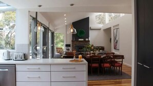 Een moderne keuken met een groot eiland, een eetgedeelte met houten stoelen en een open haard.