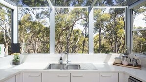Een moderne keuken met een groot raam, witte kasten en een RVS spoelbak.