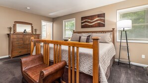 A bedroom with a bed, a wooden chair, a dresser, a mirror, a lamp, and a window with blinds.