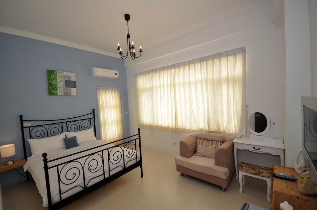 Un dormitorio con cama, sofá, televisión y ventana con cortinas.