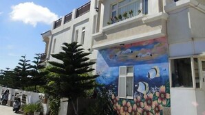 A two-story building with a mural of a lotus pond and birds on the side. - Summer Time B&B (Magong)