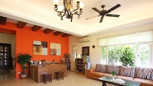 A spacious living room with a wooden ceiling, a ceiling fan, a sofa, a coffee table, and a kitchen area with a bar counter. - Summer Time B&B (Magong)