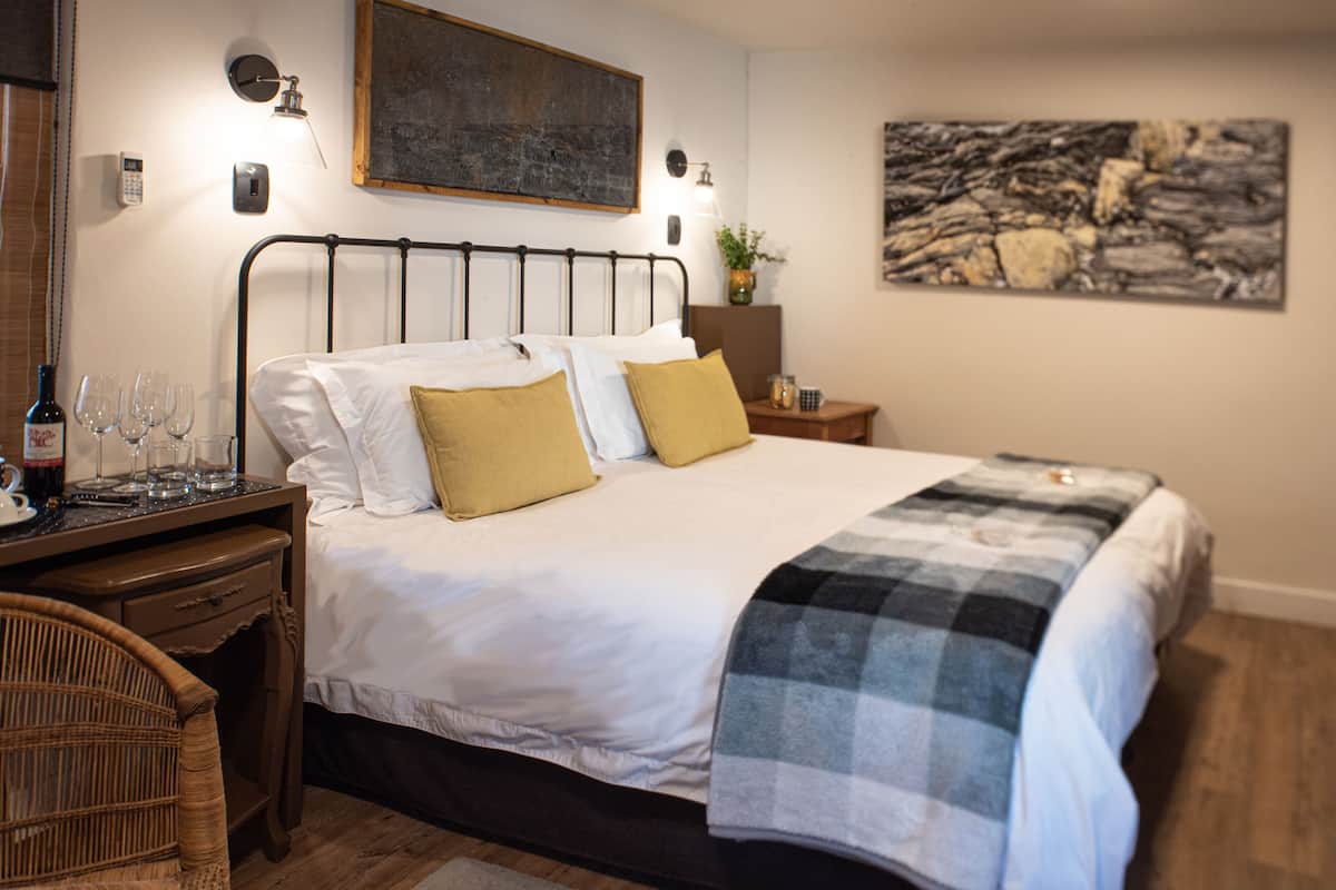 A neatly arranged bedroom with a bed, bedside table, and a chair.
