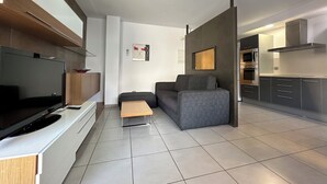 A modern living room with a flat-screen TV, grey sofa, and a wooden coffee table.