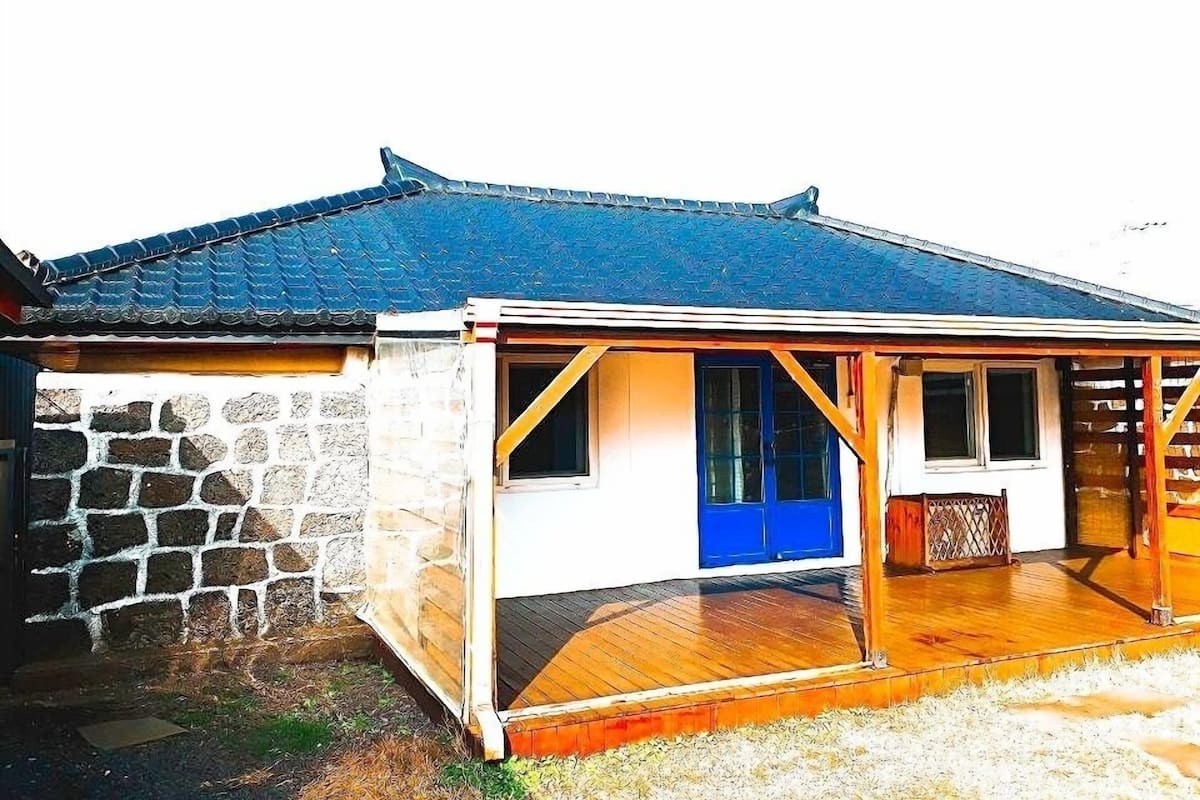 Een traditionele Japanse woning met pannendak, een stenen muur en een houten veranda.