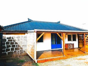 Une maison traditionnelle japonaise avec un toit en tuiles, un mur en pierre et une véranda en bois.