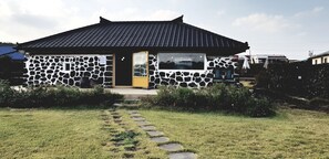Une maison en pierre avec un toit de tuiles, une porte jaune et une petite fenêtre.