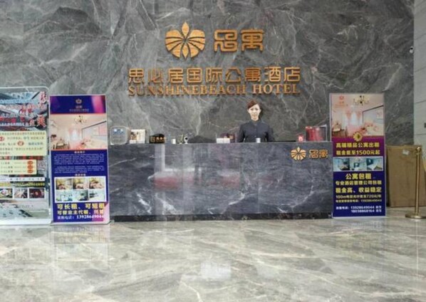 A reception desk at Sunshine Beach Hotel with a marble wall background. - Foshan Sunshinebeach Hotel (Foshan)