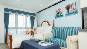Um quarto com uma cama, uma mesa de cabeceira com abajur, um sofá e uma parede decorada com quadros.