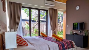 Habitación de hotel con cama, televisión y vista al exterior.
